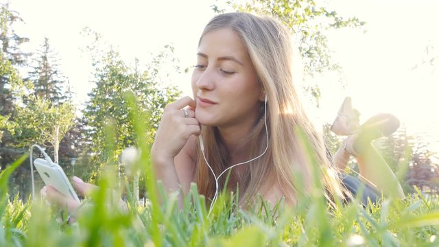 Young woman touching cell phone and lying on meadow