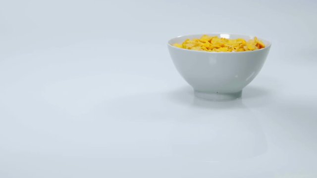 Someone is pouring some more milk into a cup full of corn flakes. This person will enjoy this very healthy breakfast. Close-up shot.
