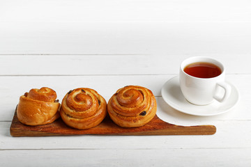 Raisin Buns and cup of tea on white table