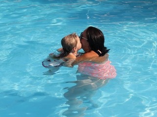 A mother and young daughter having fun in a swimming pool while on vacation, 2016