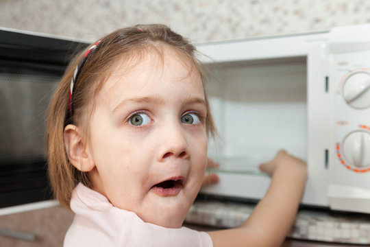 child without   parents near  microwave
