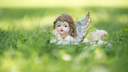 Engel Figur im Gras als Hintergrund oder Karte für Trauer, Tod oder Kondolenz und Schutzengel