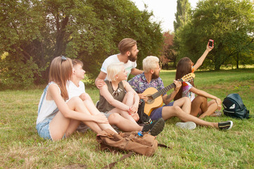 Group of smiling friends making selfie with smartphone camera in park