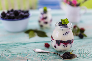 Yogurt with fresh blackberry fruit on wooden table
