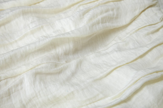 A full page close up of folds of off white colored crepe material texture