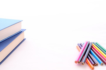 Sfondo ritorno a scuola, con matite colorate e libri, su fondo bianco con copy space