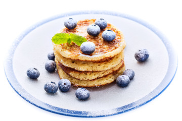 Pile of pancakes with blueberries sprinkled with icing sugar