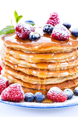 Pile of pancakes with blueberries and raspberries sprinkled with