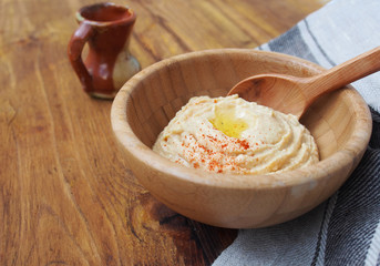Tradicional oriental hummus with olive oil and paprika in wooden bowl and wooden spoon