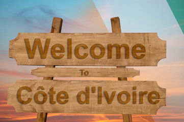 Welcome to Cote d'Ivoire sing on wood background with blending national flag