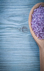 Lavender scented sea salt for skincare in wooden spoon on wood b