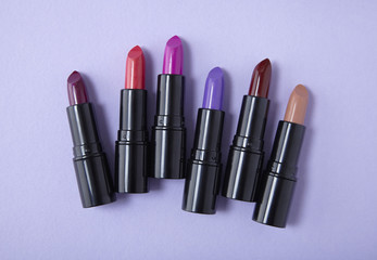 Fototapeta premium Aerial view of assorted lip stick make up on a pastel purple background