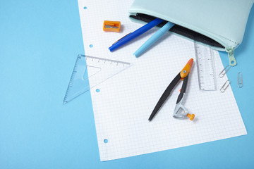 A zip pencil case with stationery spilling out on to a blue background, forming a page border