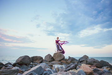 Obraz premium Young romantic woman posing on the beach watching the sunset