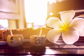 Obraz na płótnie Canvas spa concept, aromatherapy candle with fresh frangipani flower wooden table. over sunlight and warm tone [blur and select focus background]