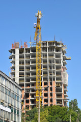 Building site with high-rise block under construction in an urban environment dominated by a large industrial crane