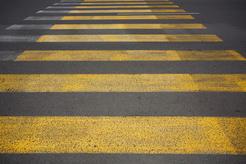 Yellow pedestrian crossing with white stripes on tarmac. Crosswalk on asphalt road. Safety marking.