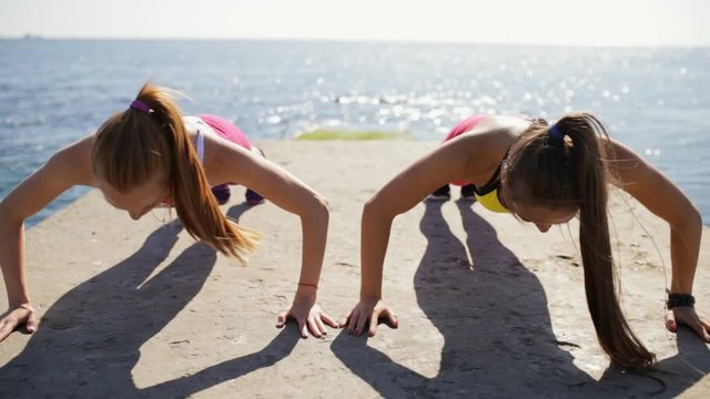 Sportswomen push ups outdoor on sea pier