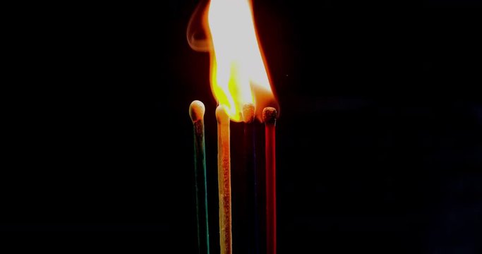 Four matches of different colours are burning together in the kitchen. Close-up shot.
