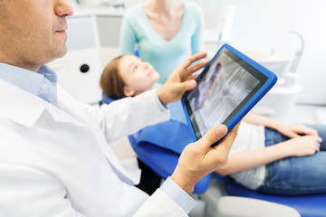 Obraz premium dentist with x-ray on tablet pc with patient girl