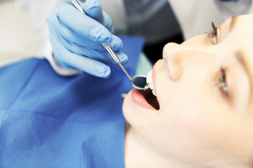close up of dentist examining female patient teeth