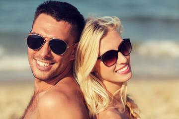 happy couple in swimwear sitting on summer beach