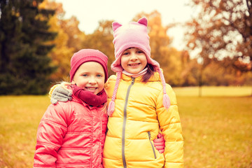two happy little girls hugging in autumn park