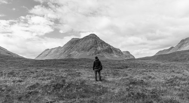 Junger Mann blickt in die Landschaft, Highlands, Schottland, Rückenansicht, schwarz weiß, Breitbild