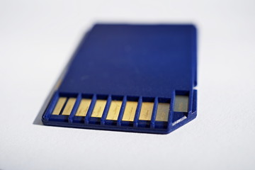 Isolated plastic compact memory card (SD card - Secure Digital card) used in cameras, computers and video cameras in a blue color with metal connectors in the golden color 