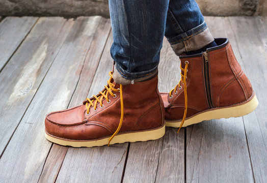 A pair of brown leather boots with laces placed on wooden floor,