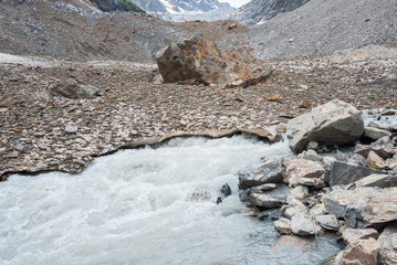 Mountain river starts right from the ice of glacial moraine. Glacier Chalaadi, the Caucasus. Near Mestia town, Svaneti, Georgia