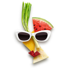 Tasty art / Quirky food concept of cubist style female face in sunglasses made of fruits and vegetables, isolated on white.