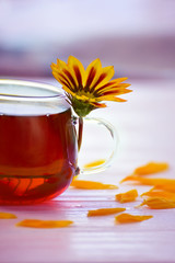 tea in a glass cup on a wooden background and yellow flowers. natural light, turquoise gentle background. 
