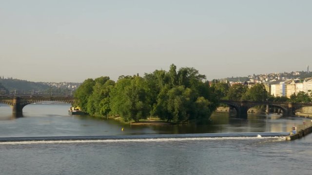 Pan across the Vltava River in Prague looking towards the Legii Bridge. A weir is seen in the foreground 