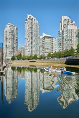 False Creek Paddling, Vancouver. Sunrise reflects off Yaletown condominiums as rowers pass by....