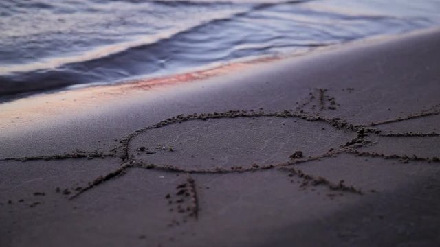 sun drawn jn beach sand washed away by waves