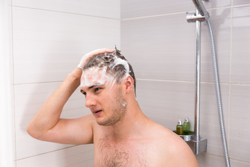 Handsome man washing his foam hair in shower cabin