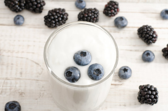Blueberries in yogurt, berries on the table, light wood background