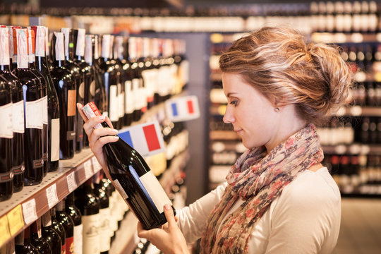 Woman trying to decide which bottle of wine to buy
