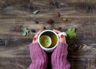 Tea with lemon in her hands. Top view