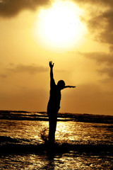 Fototapeta premium man jumping against setting sun on beach