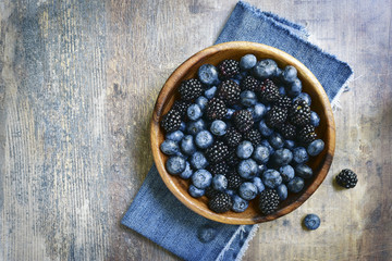 Forest berries (blueberry,bramble) in a wooden bowl.Top view.