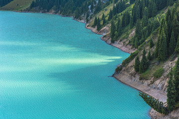 mountain lake with steep bank with trees