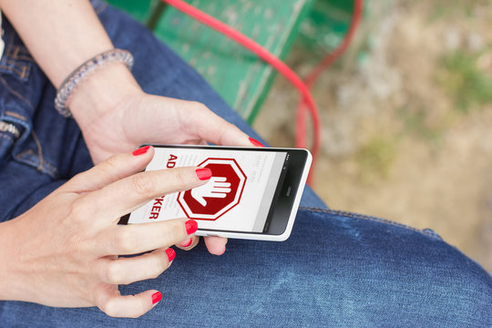 Young woman using mobile smartphone outdoors with ad blocker on