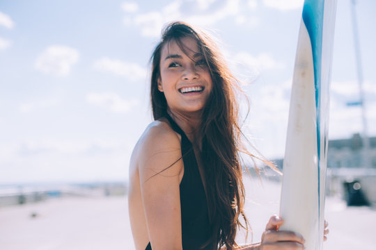 A beautiful tan girl is ready to surfing