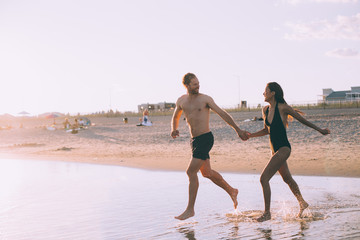 a couple is running on beach while the sun is set