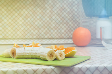 Fresh pulp banana with orange slices on kitchen table background. Blur Backside - Round fruit and blue pitcher of water. Diet, healthy concept, still life. Home made vitamin, fruits lunch. Copyspace