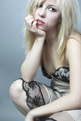 Schrille, blonde, junge Pin Up Frau im Spitzenkleid im Grunge Look