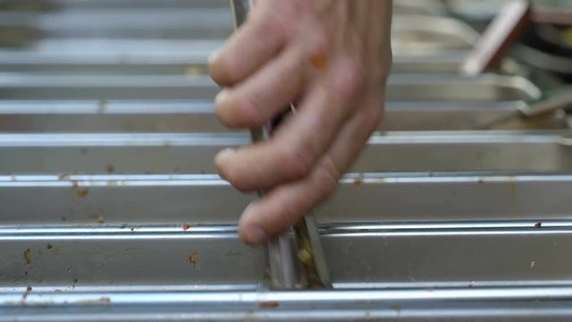 A man getting food from the chaping dish using a clip then puts them on the plate