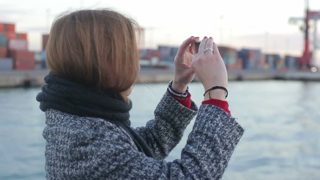 Female take photo of port infrastructure on deck of boat